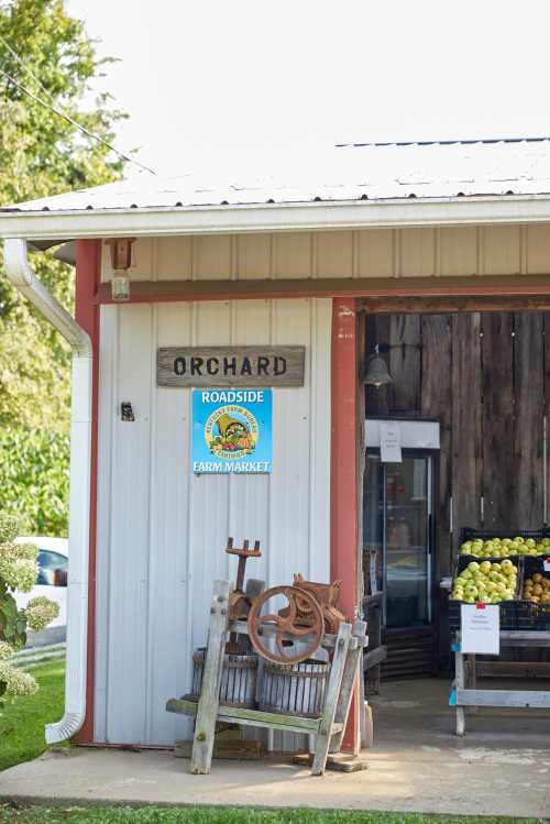 A roadside farm market with a sign reading "Orchard" and displays of fresh produce outside.