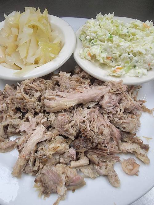 A plate with shredded meat, served with two sides: coleslaw and pickled cabbage.