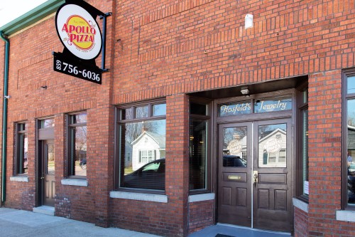 Exterior of a brick building featuring a pizza restaurant sign and a jewelry store entrance.