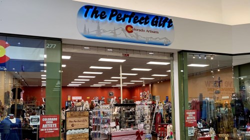 Storefront of "The Perfect Gift" featuring handmade items and crafts by Colorado artisans. Brightly lit interior.