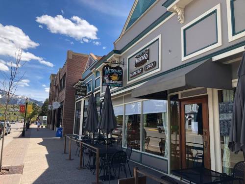 A charming street view featuring restaurants with outdoor seating and a clear blue sky in a mountain town.