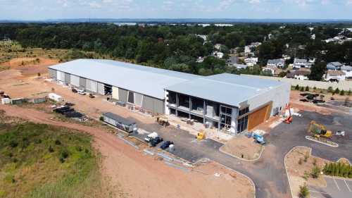 Aerial view of a large, partially constructed commercial building surrounded by dirt and machinery.