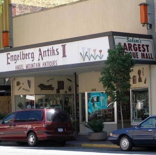 Storefront of Engelberg Antiks II, featuring a variety of antiques and a sign for Salem's largest antique mall.