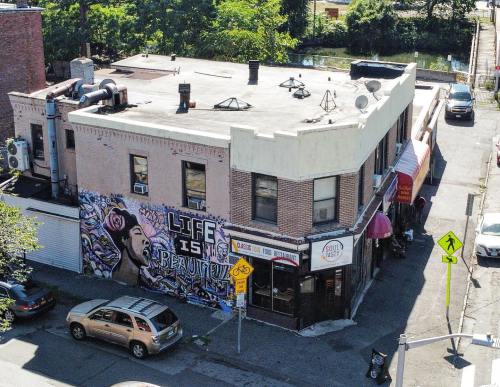 Aerial view of a building with a colorful mural reading "Life is Beautiful" and a restaurant below.