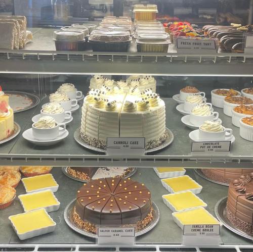 A display case filled with various desserts, including cakes, tarts, and pastries, all beautifully arranged.