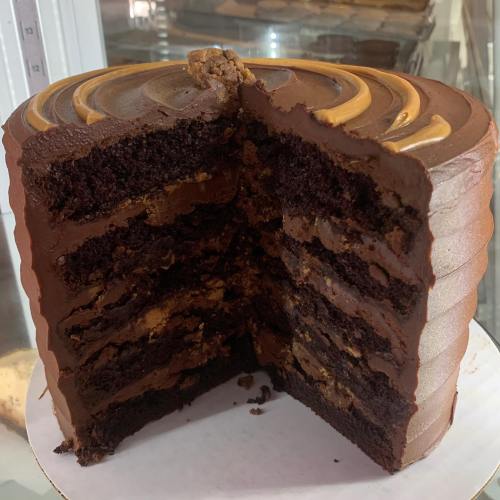 A rich chocolate cake with multiple layers, filled with chocolate frosting and a smooth, swirled top.