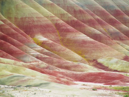 Colorful, undulating hills with vibrant red, green, and yellow stripes, showcasing a unique geological landscape.