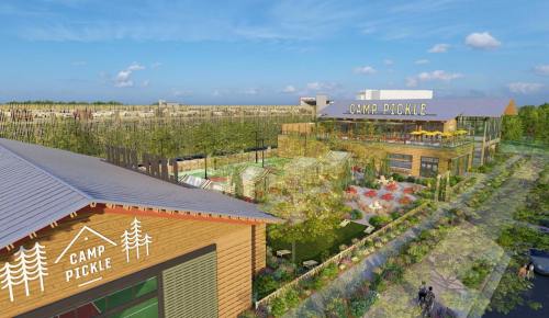 Aerial view of Camp Pickle, featuring modern buildings, greenery, and outdoor recreational spaces under a blue sky.