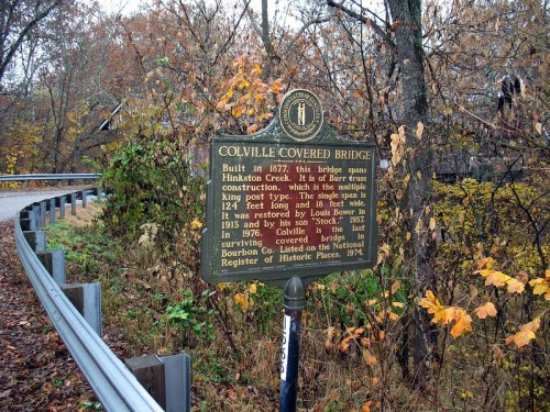 Sign about the Colville Covered Bridge, built in 1877, surrounded by autumn foliage and a winding road.