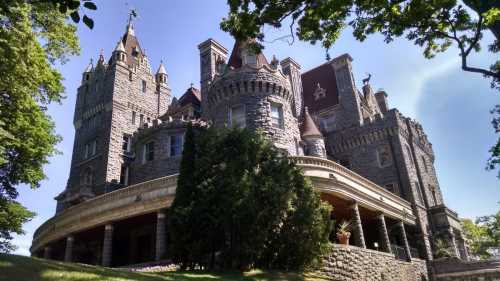 A grand stone castle with turrets, surrounded by trees and a clear blue sky.