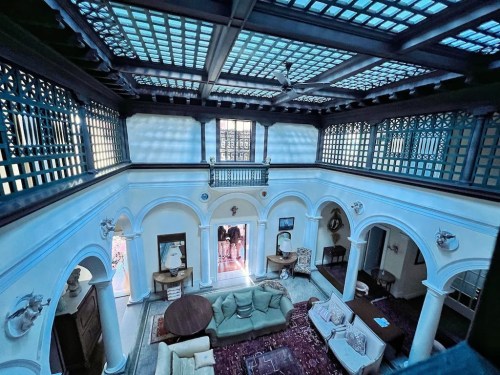 Interior view of a spacious, elegantly designed room with arched doorways, large windows, and a central seating area.