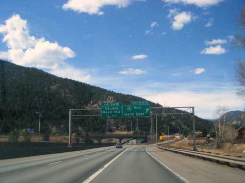 Highway exit signs for County Road 314 and Idaho Springs, with mountains and blue sky in the background.