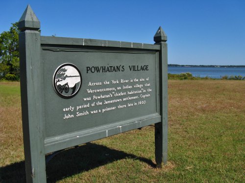 Sign for Powhatan's Village, detailing its historical significance near the York River, with a view of the water in the background.