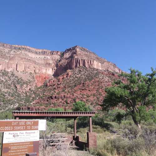 A scenic view of red rock formations and greenery, with a sign indicating day use only, near a parking area.