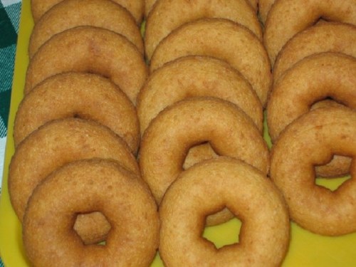 A close-up of a tray filled with golden-brown, freshly baked donuts arranged in neat rows.