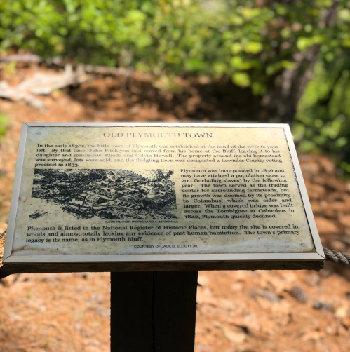 Sign about Old Plymouth Town, detailing its history and significance, surrounded by greenery.