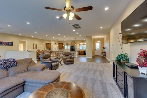 Spacious living area with a sectional sofa, ceiling fan, and open kitchen in the background. Bright and inviting atmosphere.