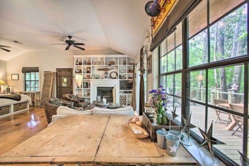 Cozy living room with a wooden table, fireplace, and large windows overlooking a deck and greenery outside.