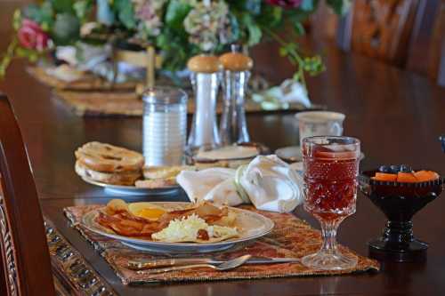 A beautifully set dining table with a plate of breakfast, including eggs, bacon, and toast, alongside a drink and condiments.