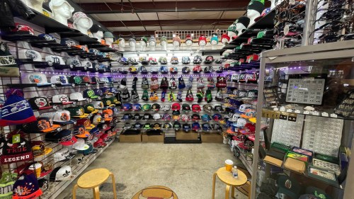 A display of various hats on shelves, with two stools in front and a coffee cup on the floor.