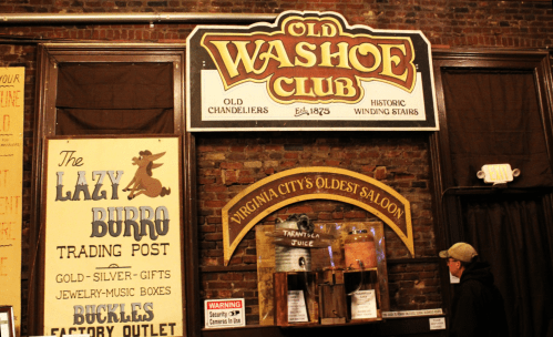 Signage for the Old Washoe Club, featuring historic details and advertisements for local businesses in a rustic setting.