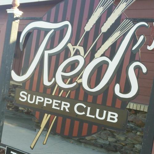 Sign for "Red's Supper Club" featuring a striped background and graphic of cooking utensils.