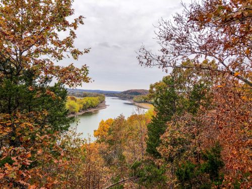 A scenic view of a river winding through autumn foliage, with trees displaying vibrant fall colors.