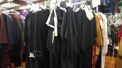 A rack of various black clothing items, including dresses and tops, in a clothing store.
