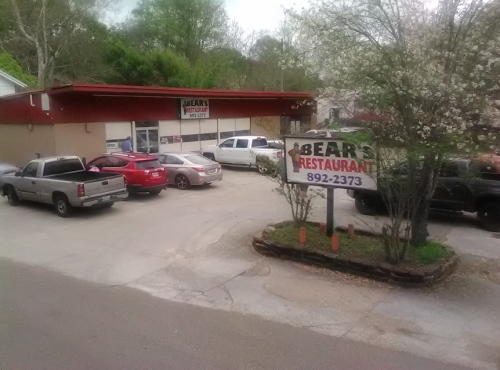 A restaurant named "Bear's" with a parking lot filled with cars and trees in the background.