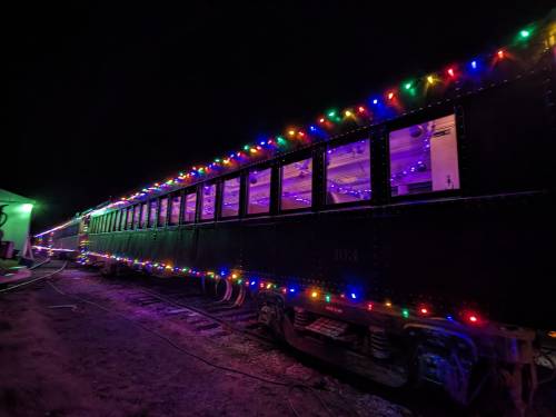 A train car decorated with colorful lights, illuminated at night, creating a festive atmosphere.