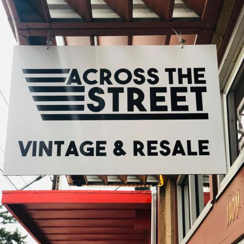 Sign for "Across the Street Vintage & Resale" displayed on a storefront, featuring bold black text on a white background.