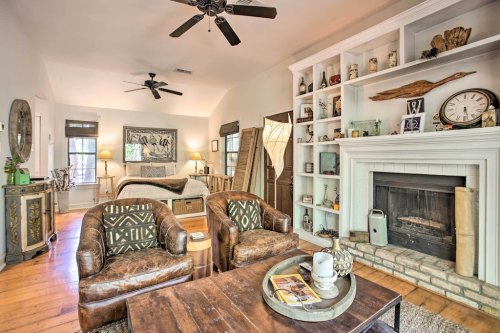 Cozy living room with two armchairs, a wooden coffee table, a fireplace, and shelves filled with decor.