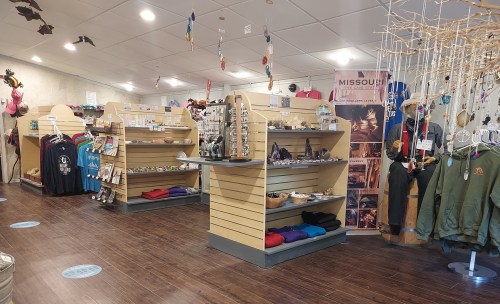 Interior of a gift shop featuring shelves of merchandise, clothing, and decorative items. Brightly lit and inviting atmosphere.
