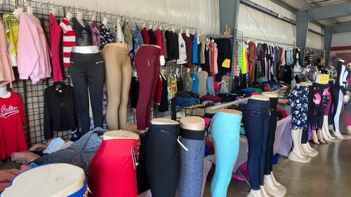 A clothing display featuring various tops and bottoms on mannequins and racks in a spacious retail setting.