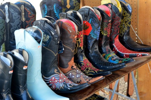 A display of colorful cowboy boots in various styles and designs, arranged on a wooden table.