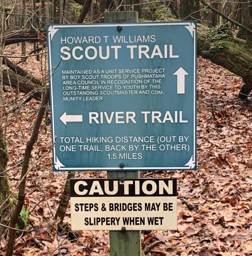 Signpost indicating Howard T. Williams Scout Trail and River Trail, with caution about slippery steps and bridges when wet.