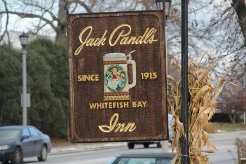 Sign for Jack Panall's Inn, established in 1915, featuring a beer mug and colorful artwork, located in Whitefish Bay.