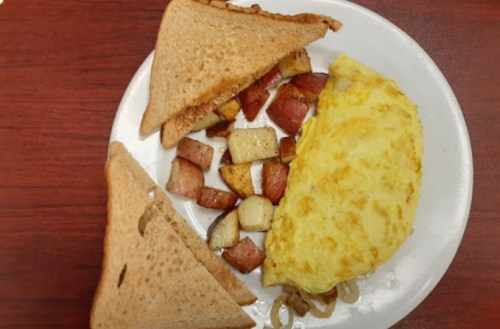 A plate with a fluffy omelet, golden-brown potatoes, and two slices of toasted whole grain bread.