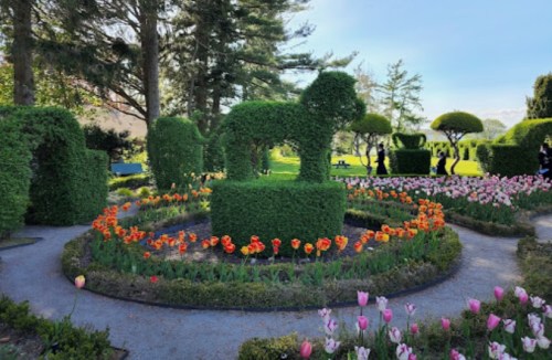 A beautifully landscaped garden featuring topiary animals and vibrant flower beds in a circular design.