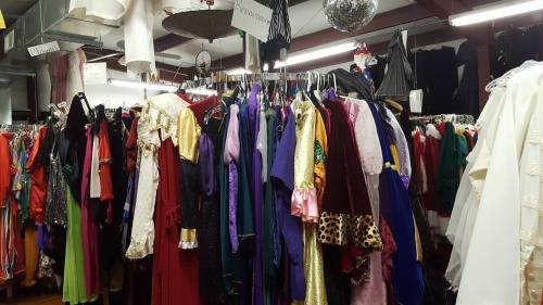 A colorful assortment of costumes hanging on racks in a costume shop, featuring various styles and fabrics.