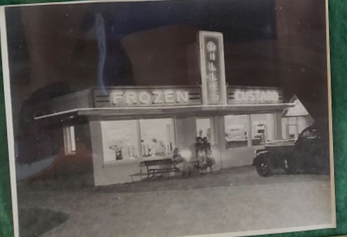 Black and white photo of a vintage ice cream shop named "Gilles Frozen Custard" with a car parked outside.
