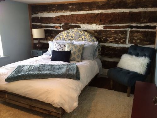 Cozy bedroom featuring a wooden accent wall, a bed with decorative pillows, and a plush chair.