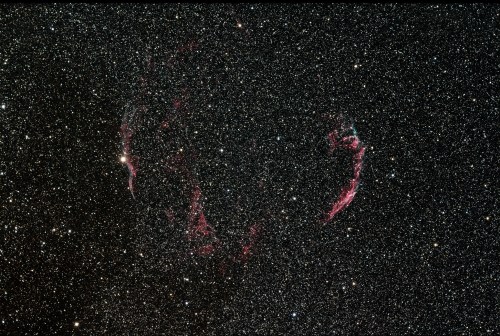 A starry night sky featuring a nebula with pinkish hues amidst countless stars.