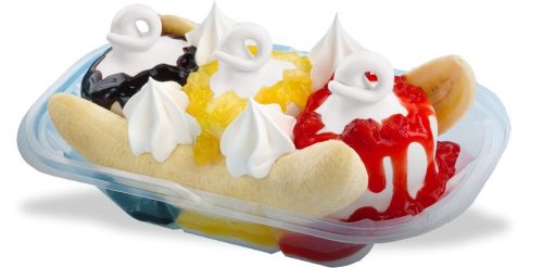 A banana split with three scoops of ice cream topped with whipped cream, chocolate, strawberry, and pineapple sauces.