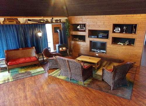 Cozy living room with wooden walls, a TV, and wicker furniture arranged around a coffee table.
