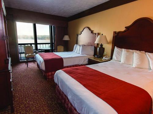 A hotel room featuring two beds, a dresser, and large windows with a view of a lake.