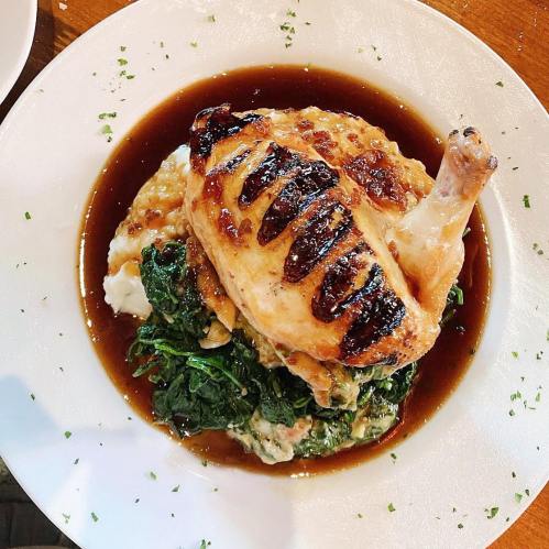 Grilled chicken breast on a bed of sautéed spinach, served with creamy mashed potatoes and a rich sauce.