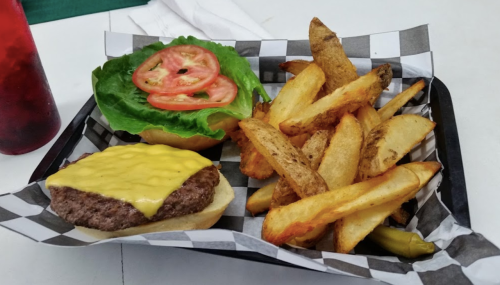 A plate with a cheeseburger topped with lettuce and tomato, alongside crispy golden fries.