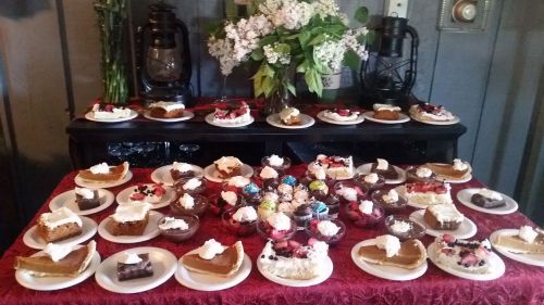 A table filled with various desserts, including cakes, pies, and cupcakes, decorated with whipped cream and berries.