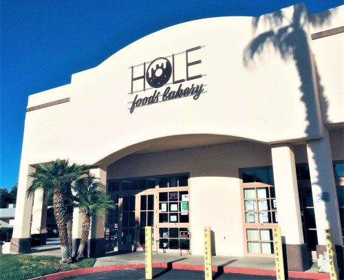 Exterior of "Hole Food Bakery" with palm trees and clear blue sky. Signage prominently displayed above the entrance.
